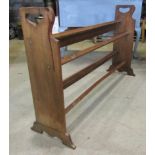 An Arts & Crafts low oak shoe rack with square rails flanked by pierced ends and shaped feet, 122 cm
