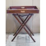 A mahogany butlers tray of rectangular form with pierced handles raised on an x framed folding