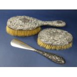 Two silver backed dressing brushes, embossed with scrolled cartouche and foliage together with a