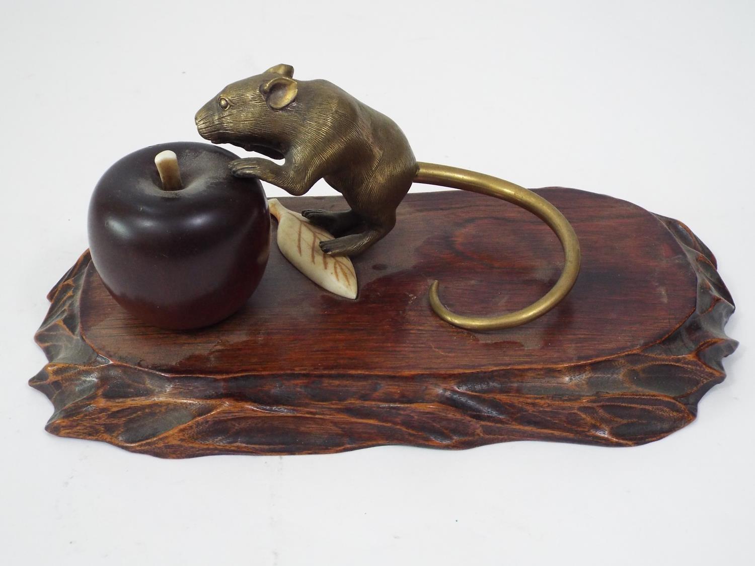 A Japanese group comprising a brass rat with gold tail, about to eat an apple, in turned wood,