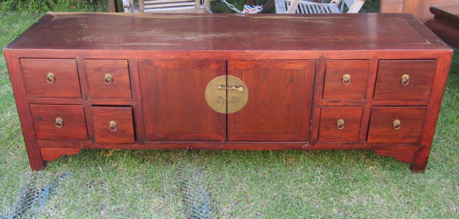 A long and low eastern hardwood side cupboard, partially enclosed by two doors, flanked by four