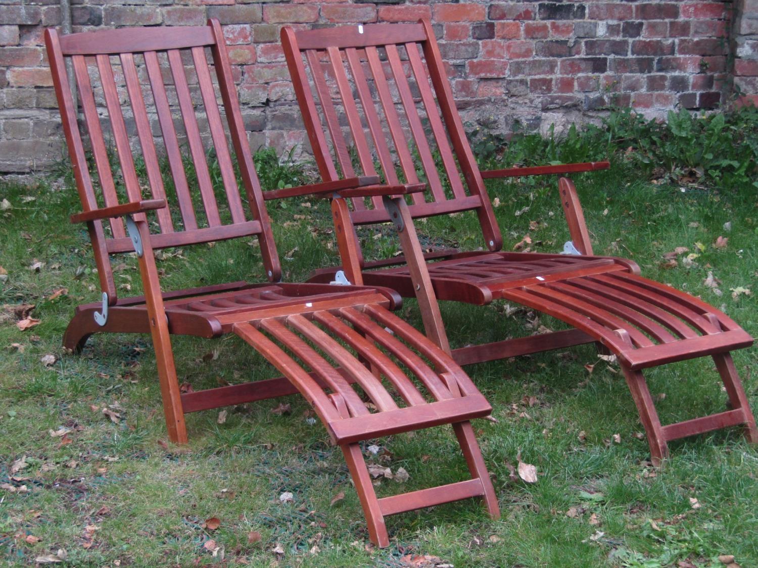 A pair of contemporary teak folding steamer type chairs with slatted seats, backs and foot rests