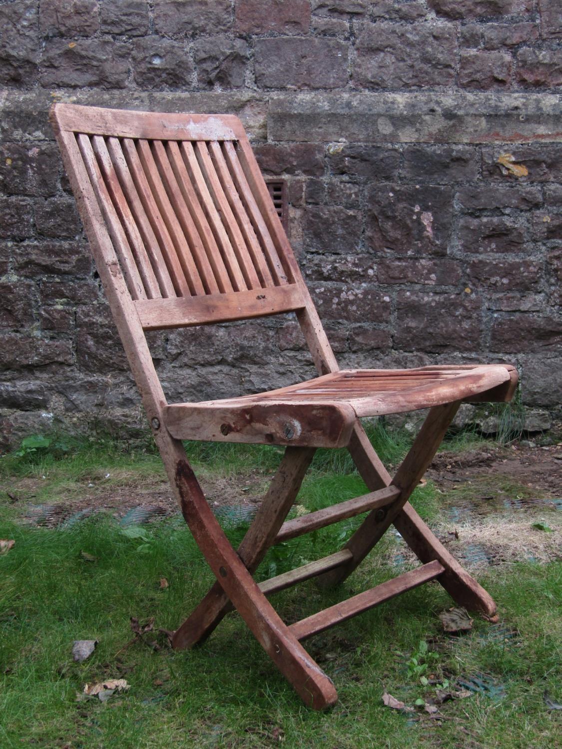 A set of eight weathered teak folding garden chairs with slatted seats and backs with oval labels to