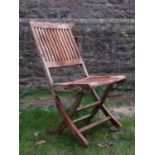 A set of eight weathered teak folding garden chairs with slatted seats and backs with oval labels to