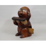 A vintage googly eyed carved timber dog supporting two clothes brushes, 25cm high