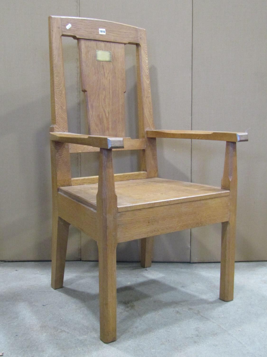 An oak open armchair with chamfered frame, solid seat, through jointed arms and broad splat, with