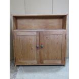 A stripped pine side cupboard/unit partially enclosed by a pair of rectangular panelled doors