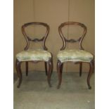 A pair of Victorian walnut balloon back dining chairs with carved foliate detail, serpentine