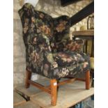 A Georgian style wing armchair with floral and fruiting vine patterned upholstered finish and