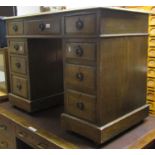 A small Edwardian oak kneehole twin pedestal writing desk fitted with the usual arrangement of