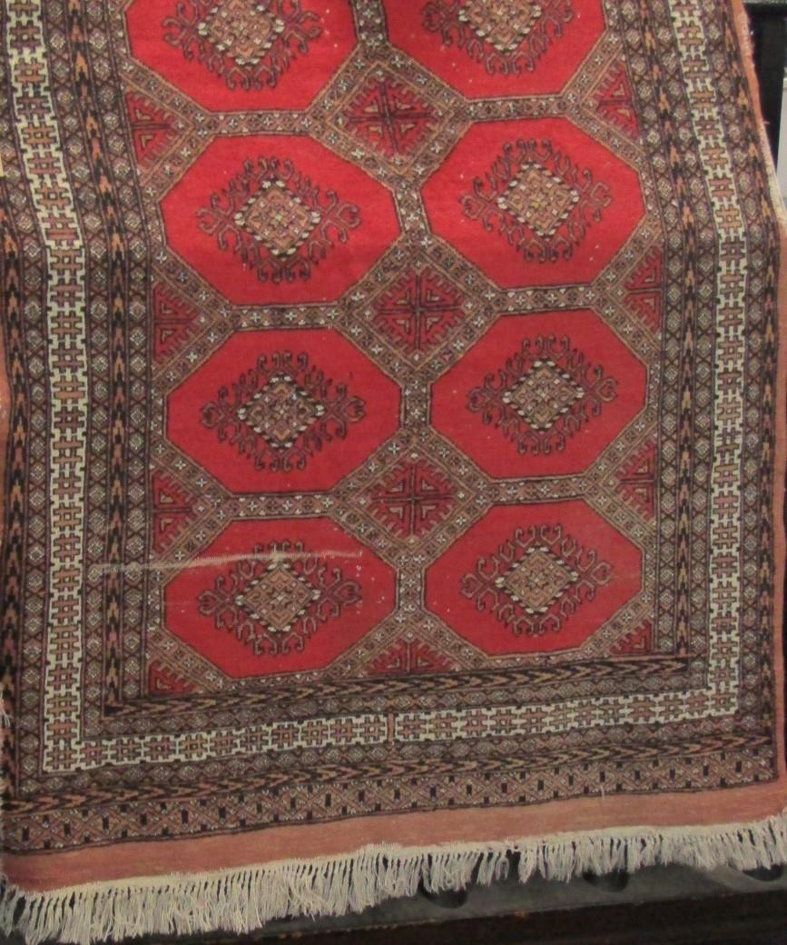 Bokhara type rug with fawn medallions upon a red ground, 200 x 130cm