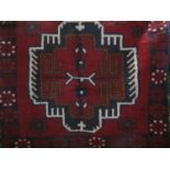 Baluchi rug with two navy blue medallion decoration upon a red ground, 136 x 90cm