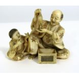 Meiji Period - Ivory Okimono of an old man amusing a young boy, by holding a rat above a cage,