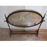 A 19th century mahogany toilet mirror, the oval mirror plate raised on turned supports, 76cm wide