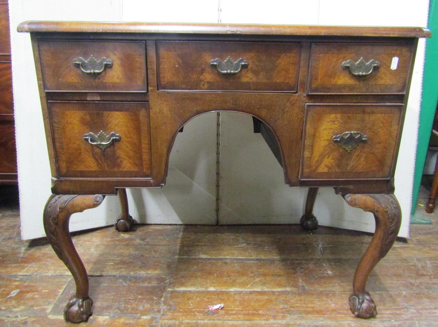 A walnut knee hole writing table in the Georgian manner, five frieze drawers around a central