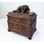 A 19th century tirolean jewel box or casket, the rising lid surmounted by a recumbent hound, the