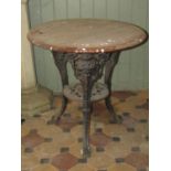 A cast iron Britannia head pub table with swept supports, pierced under tier and circular hardwood