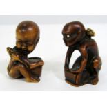 Two timber Netsuke - two small characters, both crouching and walking suspended by rats upon their