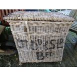 A vintage wicker two handled laundry basket with hinged lid containing a small collection of