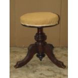 A late Victorian walnut piano stool with circular revolving adjustable upholstered seat raised on