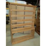 A stripped pine floorstanding open waterfall style bookcase with fixed shelves and shaped outline,