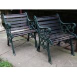 A pair of garden chairs with green painted decorative pierced and scrolling cast iron ends and