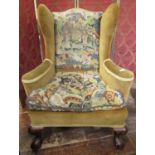 A substantial Georgian style wing chair raised on carved supports with claw and ball feet,