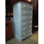 A painted pine pedestal chest of six long drawers with turned handles over a shaped apron 63 cm wide