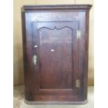 A Georgian oak hanging corner cupboard enclosed by a rectangular wavy arched moulded panelled door