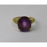 Amethyst dress ring in four prong setting, in unmarked yellow metal with scrolled shoulders, size K,