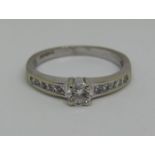 18ct white gold diamond ring set with a central round cut stone of 0.25cts approx between princess