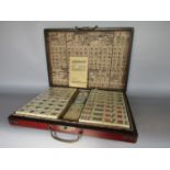 A mahjong set within a red lacquered games box, the box with gilt decoration of phoenix and dragon