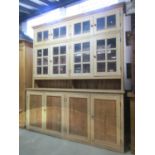 A large stripped pine farmhouse kitchen dresser, the recessed raised back enclosed by an unusual