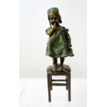 Small bronze figure after Juan Clara of a child in a green dress, bound standing on a stool, one