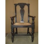 A Victorian oak open elbow chair with vase shaped splat and carved foliate detail over a drop-in
