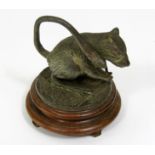 A cast figure of a rat standing on its hind legs raised on a circular hardwood base, 9 cm in height