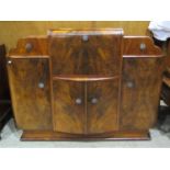 An Art Deco style walnut veneered cocktail cabinet, the central fall front enclosing a rising