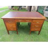 A vintage oak kneehole desk with inset faux leather writing surface over an arrangement of seven