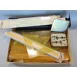 A cardboard box containing a collection of stationers tools, rulers, set squares, etc