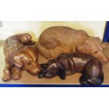 Three carved hardwood figures of recumbent hounds, 53cm long max