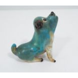 A curious opaque glass model of a humorous dog with blue and white colourway, seated pose with