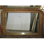 A Victorian style overmantle mirror with moulded arched gilded frame with coiled ribbon, foliate and