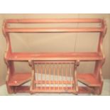 A sturdy pine wall mounted kitchen plate rack with shaped and moulded outline and inset old penny,