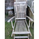 A set of six weathered teak folding garden armchairs with slatted seats and backs together with