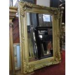 A rectangular wall mirror with bevelled edge plate within a swept stepped and moulded gilt painted