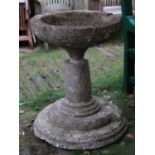 A large weathered natural stone bird bath/planter, the circular shallow bowl with notched channel