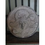 A composition stone circular wall plaque with Art Nouveau style maiden face mask and trailing