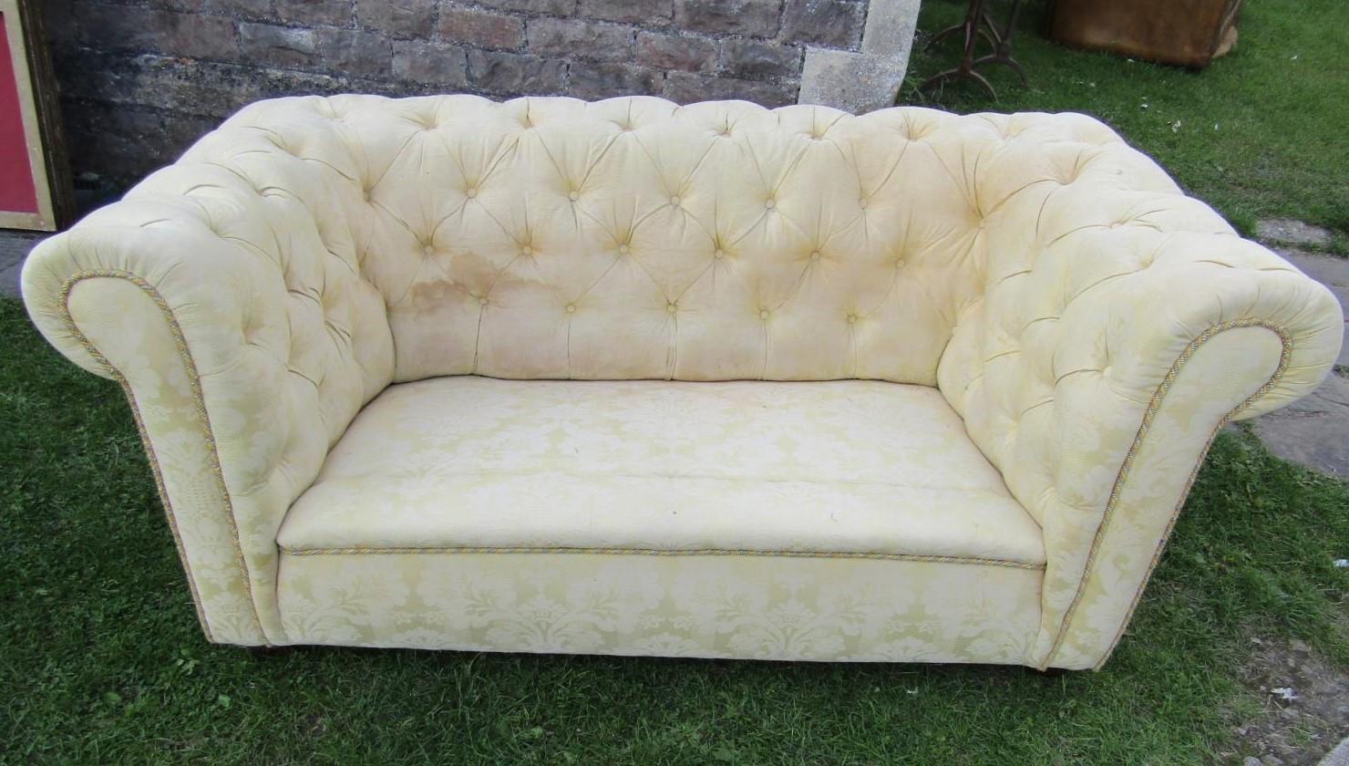 A two seat Chesterfield sofa with repeating floral pattern upholstery buttoned back and rolled arms,