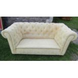 A two seat Chesterfield sofa with repeating floral pattern upholstery buttoned back and rolled arms,