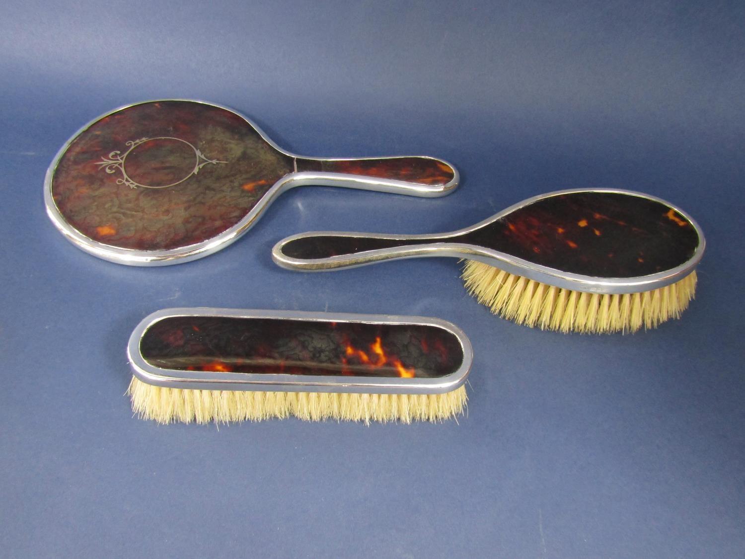 Matched three piece silver and tortoiseshell dressing set comprising mirror and two brushes (3)